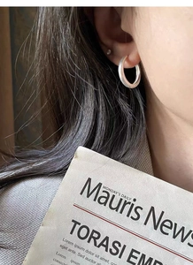 Close-up of minimalist brushed S925 sterling silver hoop earring worn by a model