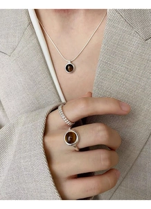 Detailed view of S925 silver tiger eye stone ring set worn on model over grey fabric