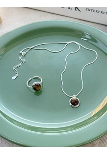 Tiger's eye stone necklace and ring set on dark green ceramic plate with silver chain
