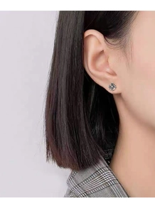 Macro shot of silver retro cross stud earring worn on ear with vintage oxidized finish
