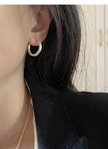 Close-up of minimalist brushed S925 sterling silver hoop earring worn by a model
