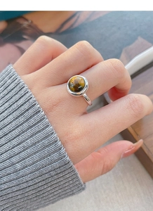 Close-up of S925 sterling silver ring with a round tiger eye stone on a model's finger