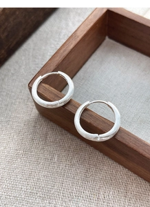 Detail of S925 sterling silver hoop earring with a brushed matte finish on wood