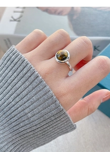 Detail of a vintage S925 sterling silver ring with a round tiger eye stone on a finger