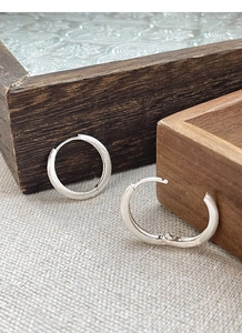 Detail of S925 sterling silver hoop earrings with a matte brushed finish on fabric