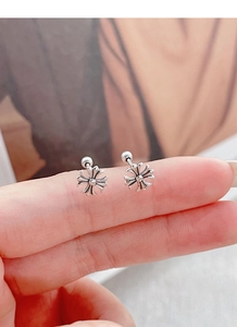 Detail of S925 silver cross stud earring with screw back closure held between fingers
