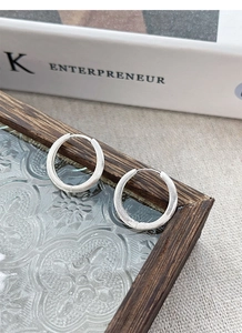 Detail of S925 sterling silver hoop earrings with a matte brushed texture on a vintage tray