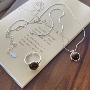 S925 Sterling Silver necklace and tiger eye ring set on a rustic vintage background