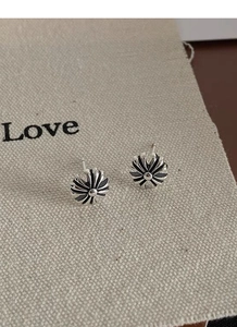 Detailed view of vintage S925 sterling silver cross stud earring on rustic linen background
