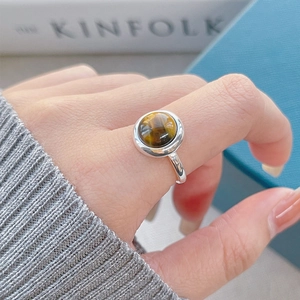 Polished S925 sterling silver ring with round tiger eye stone shown on a finger