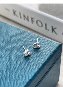 Détail de boucles d'oreilles souris en argent S925 et zircons sur un écrin à bijoux bleu