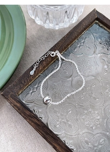 Close-up of minimalist S925 sterling silver beaded bracelet on a vintage glass tray