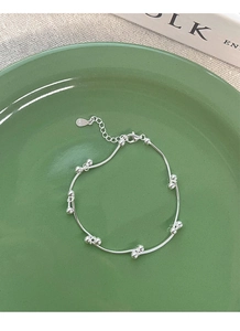 Detail of S925 sterling silver bean knot bracelet with lobster clasp on olive ceramic plate