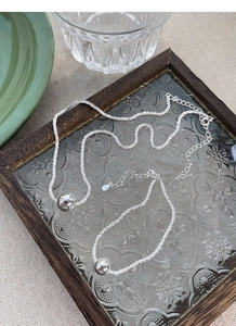 Macro detail of S925 sterling silver beaded bracelet and lobster clasp on glass tray