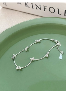 Close-up of S925 sterling silver bean knot bracelet with beads on dark green plate