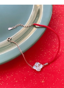 Détail macro du pendentif Fu en argent S925 sur bracelet rouge avec nacre blanche