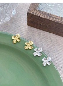 Detail view of gold and silver S925 sterling silver gardenia flower stud earrings