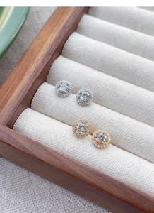 Vue détaillée de boucles d'oreilles halo en argent et or avec zircons dans un coffret