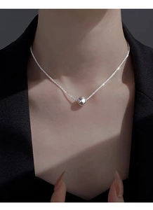 Macro detail of minimalist S925 sterling silver ball necklace with shimmering chain