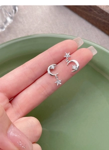Macro detail of S925 sterling silver star and moon earrings with sparkling zircon stones
