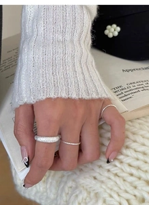 Three-piece silver ring set featuring frosted texture and braided band designs on model