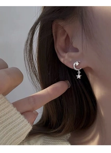 Detail of S925 sterling silver star and moon earrings with cubic zirconia on a model