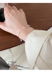 Close-up of minimalist silver wave bracelet with bead accents on female wrist