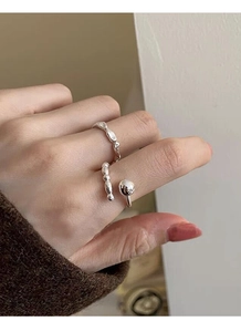 Detail of stacked S925 sterling silver beaded and wavy open rings on a female finger