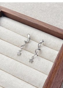 Macro shot of S925 sterling silver star fringe earrings on a beige jewelry display box