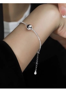 Macro shot of minimalist S925 sterling silver ball bracelet with polished bead on wrist
