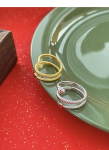 Macro detail of gold and silver snake rings with intricate scale textures on a green plate