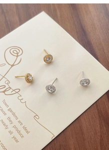 Détails de boucles d'oreilles rondes en zircon argenté et doré sur carte vintage