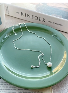 Detail view of S925 silver pearl necklace on elegant green tray with fine chain