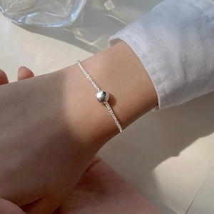 Minimalist S925 sterling silver beaded bracelet on wrist with polished silver charm