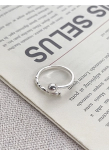 Detailed close-up of a minimalist silver beaded ring on a vintage newspaper background