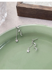 Macro detail of S925 sterling silver spinning star earrings with tassel and pavé star charm