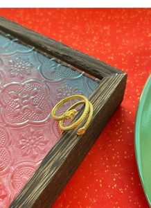 Close-up of golden vintage snake ring with scale textures on a decorative wood tray