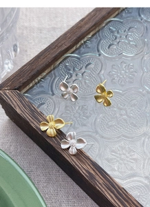 Detailed macro view of S925 silver gardenia flower earrings in matte gold and silver finish