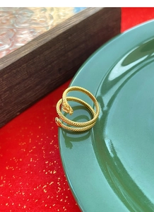 Detailed macro shot of vintage gold snake ring with realistic scales on green ceramic