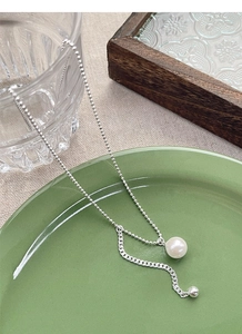 Detail of S925 silver pearl necklace with bead chain on a ceramic plate tray