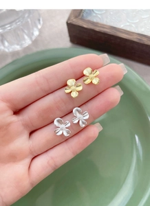 Detailed close-up of matte S925 sterling silver gardenia flower earrings in gold and silver