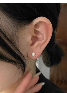 Detailed close-up of a S925 sterling silver camellia stud earring on a female ear