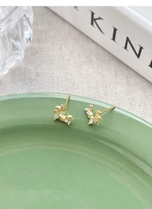 Detailed close-up of gold leaf cluster earrings with marquise-cut sparkling zircon stones