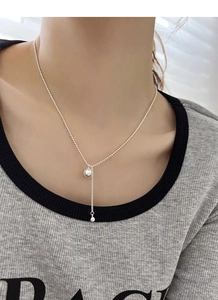 Detail of S925 silver pearl necklace with tassel pendant worn by a model on the neck