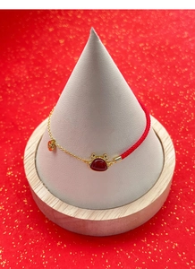 Détail du bracelet en corde rouge avec pendentif dragon doré et perle en agate rouge