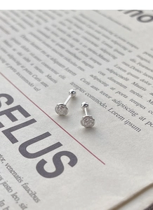 Detail of S925 silver camellia stud earrings with secure screw ball back on vintage paper