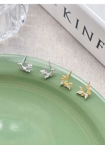 Macro detail of wheat ear stud earrings in silver and gold with marquise-cut zircons