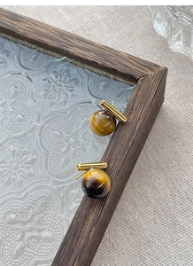 Detailed view of S925 silver tiger eye stud earrings with gold bar on linen background