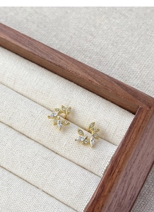Macro detail of golden wheat ear earrings with marquise zircons in a wooden jewelry box