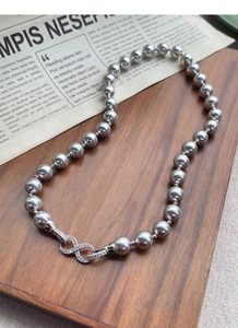 Macro shot of dark grey pearl necklace featuring a diamond-encrusted infinity clasp